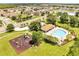 Community aerial view showcasing pool, clubhouse, and playground amidst green spaces and manicured landscaping at 2810 Maguire Dr, Kissimmee, FL 34741