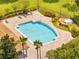 Aerial view of a large community pool, lush landscaping, sun loungers, and rock waterfall feature at 2810 Maguire Dr, Kissimmee, FL 34741