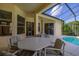 Covered patio area featuring an outdoor dining set, adjacent to a screened-in pool at 305 Grand Reserve Dr, Davenport, FL 33837