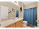 Neat bathroom with neutral walls, a vanity with a large mirror, and a shower with a blue curtain at 3125 Grasmere View Pkwy, Kissimmee, FL 34746