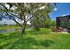 Expansive backyard featuring a well-manicured lawn, lush trees, and screened lanai with a scenic water view at 346 Treviso Dr, Kissimmee, FL 34759