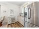 Kitchenette features stainless steel refrigerator, white cabinetry, and wooden-look tile flooring at 346 Treviso Dr, Kissimmee, FL 34759
