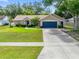 Inviting single-story home featuring a well-kept lawn, mature trees, and a blue two-car garage door at 4828 Jeanette Ct, St Cloud, FL 34771