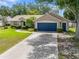 Attractive single-story home with a well-manicured lawn, mature trees, and a blue two-car garage door at 4828 Jeanette Ct, St Cloud, FL 34771