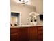 Bathroom featuring wooden cabinets, white countertops, a large mirror, and modern lighting fixtures at 6100 Stevenson Dr # 202, Orlando, FL 32835