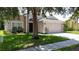 Inviting home with a two-car garage, manicured lawn, and mature trees providing shade at 838 Sandy Ridge Dr, Davenport, FL 33896