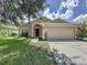 Charming single-Gathering home featuring a two-car garage and a well-maintained front lawn with mature trees at 838 Sandy Ridge Dr, Davenport, FL 33896