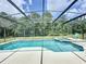 Screened-in pool with spa and pool deck overlooking the wooded backyard at 838 Sandy Ridge Dr, Davenport, FL 33896