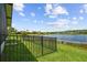 Lawn overlooks lake beyond wrought iron fence at 925 Grand Canal Dr, Poinciana, FL 34759