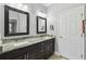 Elegant bathroom with dual sinks, dark wood cabinetry, granite counters, and well-lit mirrors at 925 Grand Canal Dr, Poinciana, FL 34759
