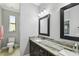 Well-lit bathroom featuring dual mirrors, marble countertops, and a nearby toilet and window at 925 Grand Canal Dr, Poinciana, FL 34759