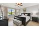 Spacious main bedroom with a large bed, ceiling fan, dresser, and scenic lake view through large windows at 925 Grand Canal Dr, Poinciana, FL 34759