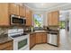 Kitchen with stainless steel appliances, wood cabinetry, and light countertops at 925 Grand Canal Dr, Poinciana, FL 34759