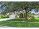 Home's front yard showcases lush green grass, a mature tree, and a clean sidewalk and driveway at 14287 E Weymouth Run, Orlando, FL 32828