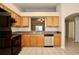 Kitchen area featuring tile floors, wood cabinets, a stainless-steel dishwasher, and a bar-style pass through at 1749 Christina Lee Ln, St Cloud, FL 34769