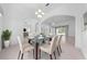 Light dining room with a modern glass table and six chairs set under a chandelier at 1810 Lee Janzen Dr, Kissimmee, FL 34744