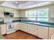 Bright kitchen featuring white appliances, white cabinets, laminate counters, and wood-look flooring at 1921 Japonica Rd, Winter Park, FL 32792