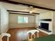 Spacious living room featuring wood floors, ceiling fan, exposed beams, and a cozy brick fireplace at 1921 Japonica Rd, Winter Park, FL 32792