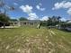 Exterior front view of olive drab house and partially overgrown lawn with a small tree and fence line at 2549 Olive Ave, Lake Wales, FL 33898