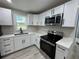 Well-lit kitchen with stainless steel appliances, white cabinets, quartz countertops, and modern fixtures at 2549 Olive Ave, Lake Wales, FL 33898
