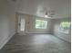 Open living room with gray vinyl floors, ceiling fan, back door, and natural light from the multiple windows at 2549 Olive Ave, Lake Wales, FL 33898