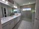 Bathroom featuring a double sink vanity, quartz countertops, and a large glass enclosed shower with a transom window at 2853 Willowseed Ln, St Cloud, FL 34772