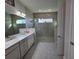 View of a bathroom with gray tiled floors and walls, double vanity, and a walk-in glass shower at 2853 Willowseed Ln, St Cloud, FL 34772