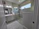 A bathroom featuring a double sink vanity with a quartz countertop and a glass enclosed shower with a transom window at 2853 Willowseed Ln, St Cloud, FL 34772