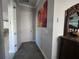 A hallway with gray carpet, gray walls, a white door, and a decorative dresser with a mirror at 2853 Willowseed Ln, St Cloud, FL 34772