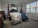 Elegant main bedroom featuring a four-poster bed, seating area, and large window for natural light at 2853 Willowseed Ln, St Cloud, FL 34772