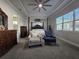Bright main bedroom featuring a tray ceiling, four-poster bed, seating, and a view to the ensuite bathroom at 2853 Willowseed Ln, St Cloud, FL 34772