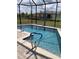 Sparkling screened-in pool with a safety handrail, a patio, and a well-maintained backyard at 3184 Songbird Cir, Harmony, FL 34773