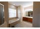 Bathroom showcasing a soaking tub, double sink vanity with cabinets, and tile flooring at 406 Cinnamon Dr, Kissimmee, FL 34759