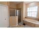 Neutral bathroom featuring a walk-in shower, soaking tub with tile surround and a window for natural light at 406 Cinnamon Dr, Kissimmee, FL 34759