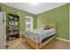 Well-lit bedroom featuring hardwood floors, a natural wood bed frame, and green walls at 608 Wechsler Cir, Orlando, FL 32824