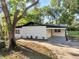 Charming home with a white exterior, black roof, and a covered carport at 7043 Carlene Dr, Orlando, FL 32835