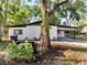 Charming home with a white exterior, black roof, and a covered carport at 7043 Carlene Dr, Orlando, FL 32835