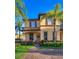Charming two-story townhome featuring a welcoming porch, lush landscaping, and two palm trees enhancing curb appeal at 746 Terra Lago St, Davenport, FL 33897