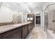 Bathroom featuring a soaking tub, glass shower, double vanity with granite counters, and closet access at 9121 Laureate Blvd, Orlando, FL 32827