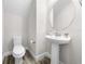 Clean half bathroom with pedestal sink, round mirror, and wood-look tile flooring at 9121 Laureate Blvd, Orlando, FL 32827