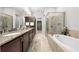 Bathroom featuring a soaking tub, glass shower, double vanity with granite counters, and closet access at 9121 Laureate Blvd, Orlando, FL 32827