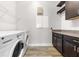 Laundry room with side-by-side washer and dryer, wood-look tile floors, and dark wood cabinets at 9121 Laureate Blvd, Orlando, FL 32827