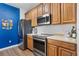 Modern kitchen with stainless steel appliances, blue accent wall, and wood cabinets at 1351 Venezia Ct # 201, Davenport, FL 33896