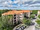 Wide angle aerial of condo building with red tile roof, tropical landscaping and ample parking spaces at 1361 Tuscan Ter # 7303, Davenport, FL 33896