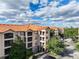 Low aerial of condo building with red tile roof, tropical landscaping and ample parking spaces at 1361 Tuscan Ter # 7303, Davenport, FL 33896