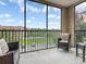 Screened patio featuring a cushioned wicker chair and table with a scenic view of the community at 1361 Tuscan Ter # 7303, Davenport, FL 33896