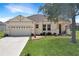 Inviting one-story home featuring a well-manicured lawn, two-car garage, and charming front porch at 1405 Hillsborough Way, Kissimmee, FL 34759
