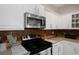 Bright kitchen featuring white cabinets, stainless steel microwave, and tile backsplash at 1405 Hillsborough Way, Kissimmee, FL 34759
