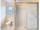 Bright bathroom featuring a shower with sliding glass doors, a toilet, and a window with blinds at 1515 Oak Hill Trl, Kissimmee, FL 34747