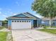 Charming blue single-story home with a well-manicured lawn and a white two-car garage at 1515 Oak Hill Trl, Kissimmee, FL 34747